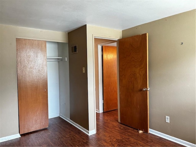 unfurnished bedroom featuring dark wood-type flooring and a closet