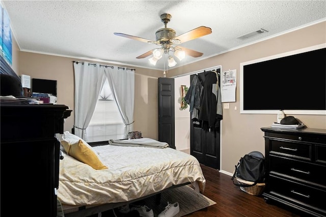 bedroom with ceiling fan, crown molding, dark wood-type flooring, and a textured ceiling