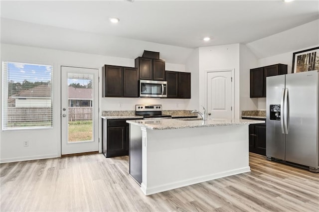 kitchen featuring a kitchen island with sink, sink, vaulted ceiling, appliances with stainless steel finishes, and dark brown cabinets