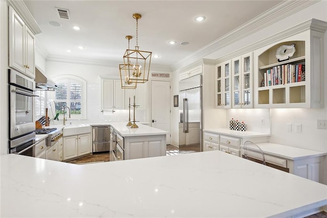 kitchen with white cabinetry, sink, hanging light fixtures, stainless steel appliances, and a kitchen island