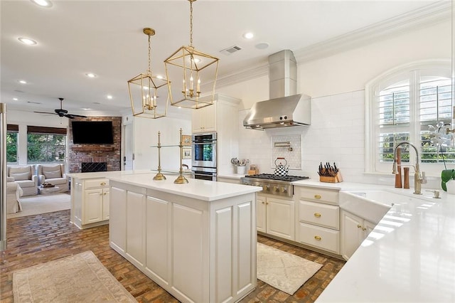 kitchen with appliances with stainless steel finishes, a kitchen island, a fireplace, and exhaust hood