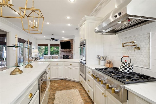 kitchen featuring ceiling fan with notable chandelier, tasteful backsplash, white cabinetry, and exhaust hood