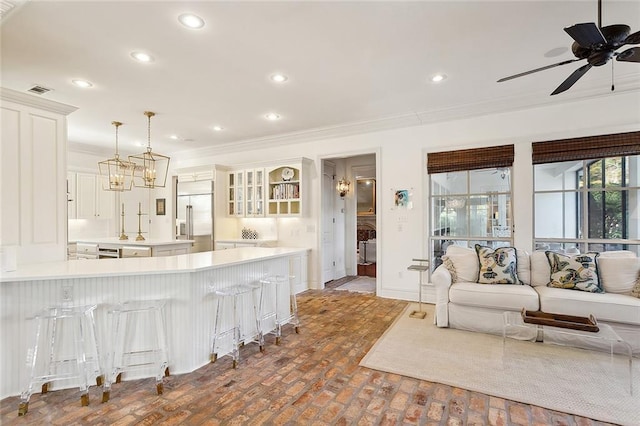 kitchen with ceiling fan, a kitchen breakfast bar, pendant lighting, stainless steel built in fridge, and ornamental molding