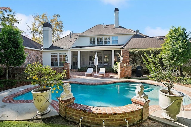 view of swimming pool with a sunroom and a patio area