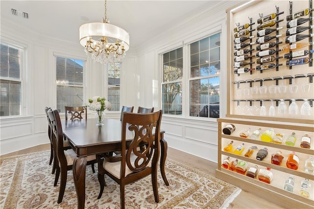 dining area featuring wood-type flooring, crown molding, and a chandelier