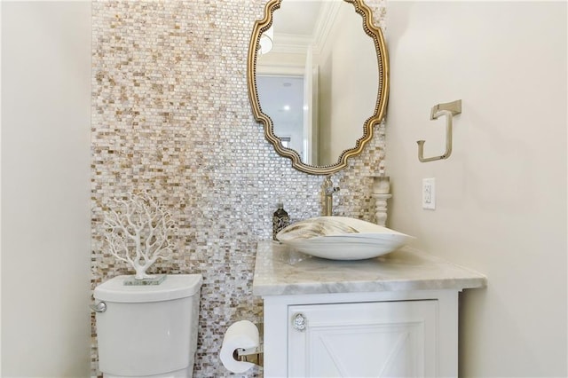 bathroom with vanity, toilet, ornamental molding, and backsplash