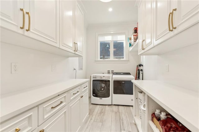 laundry room featuring cabinets, washing machine and dryer, light hardwood / wood-style flooring, and ornamental molding