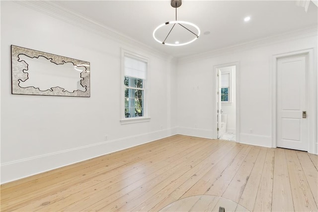 empty room featuring light wood-type flooring and ornamental molding