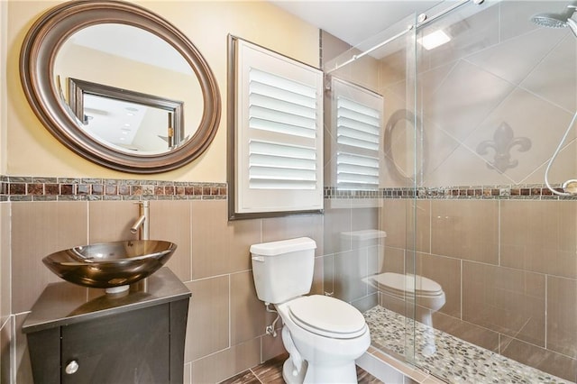 bathroom with vanity, toilet, tile walls, and a shower with shower door