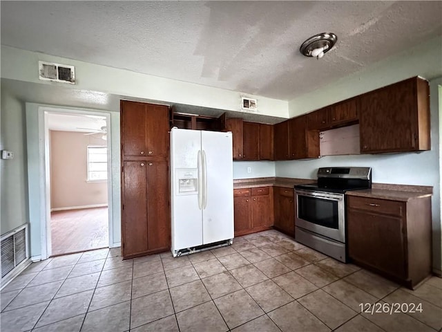 kitchen with a textured ceiling, stainless steel range with electric cooktop, light tile patterned flooring, and white refrigerator with ice dispenser