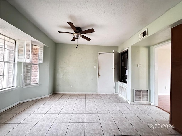 tiled spare room with a textured ceiling and ceiling fan