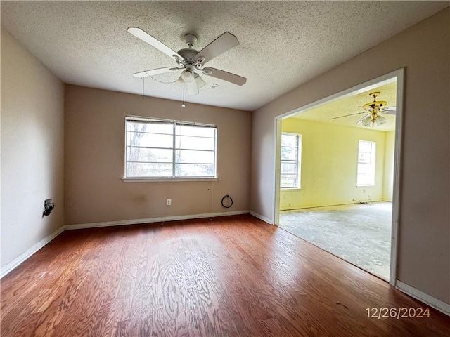 empty room with a wealth of natural light, ceiling fan, and a textured ceiling