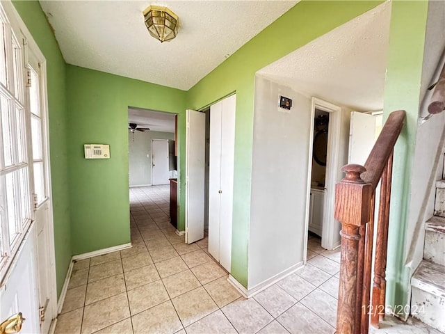 hallway featuring a textured ceiling and light tile patterned flooring