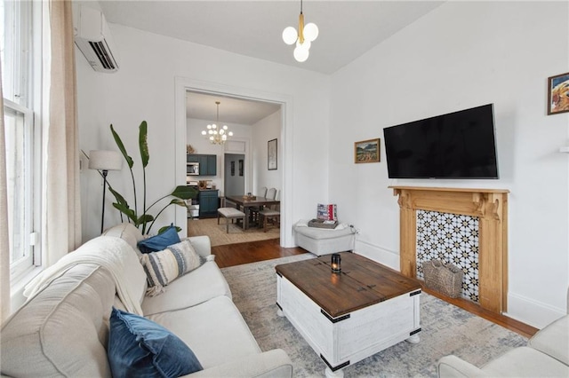 living room with a chandelier, a wall mounted air conditioner, wood finished floors, and baseboards