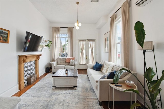 living room featuring hardwood / wood-style flooring, a wall mounted AC, and a chandelier