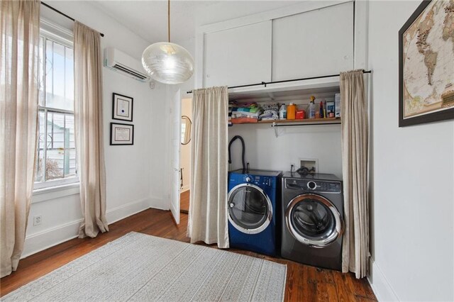 clothes washing area with plenty of natural light, dark hardwood / wood-style flooring, a wall unit AC, and washing machine and clothes dryer