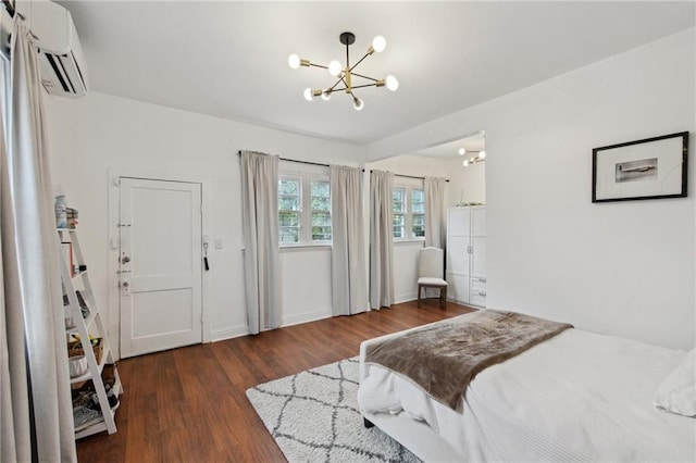 bedroom with a wall unit AC, an inviting chandelier, baseboards, and dark wood-type flooring