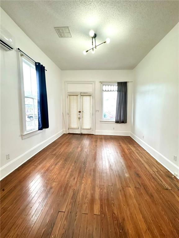 interior space featuring dark wood-style floors, visible vents, a textured ceiling, and baseboards