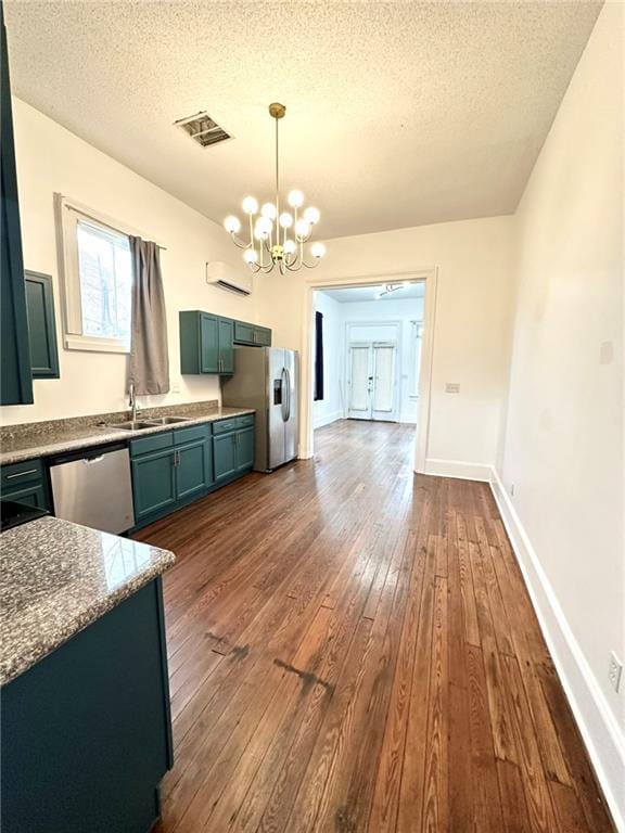 kitchen with light stone counters, decorative light fixtures, visible vents, appliances with stainless steel finishes, and a sink