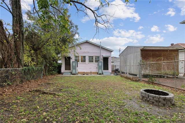 back of house with entry steps, fence, and a fire pit