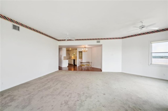 unfurnished living room featuring ceiling fan with notable chandelier and carpet floors