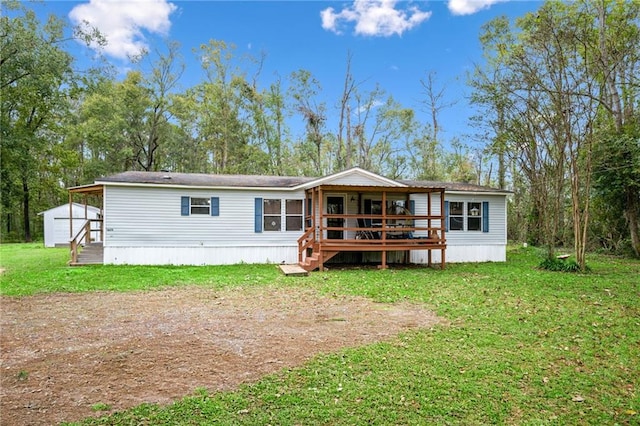 rear view of property featuring a garage, an outdoor structure, a yard, and a wooden deck