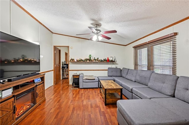 living room featuring ceiling fan, hardwood / wood-style floors, vaulted ceiling, a textured ceiling, and ornamental molding