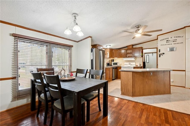 dining space featuring light hardwood / wood-style floors, ornamental molding, a textured ceiling, and vaulted ceiling