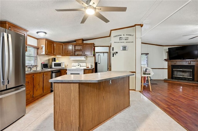 kitchen featuring vaulted ceiling, ornamental molding, a textured ceiling, appliances with stainless steel finishes, and a kitchen island