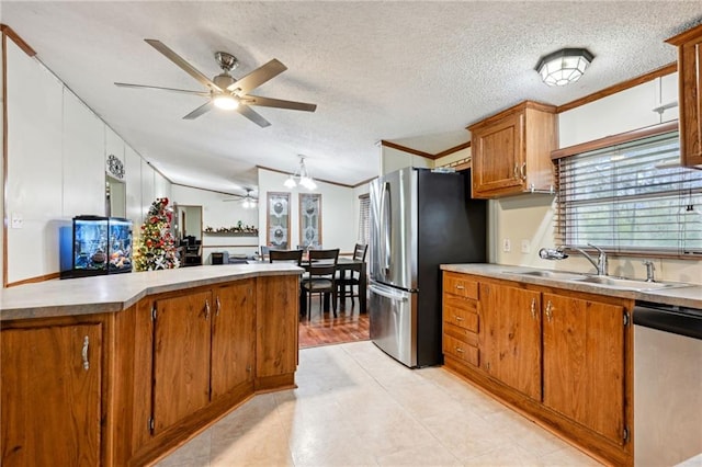 kitchen featuring sink, stainless steel appliances, a textured ceiling, vaulted ceiling, and ornamental molding