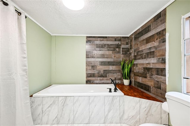 bathroom with crown molding, toilet, a textured ceiling, and tiled tub