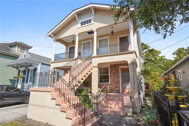 view of front of house featuring stucco siding, a porch, and brick siding