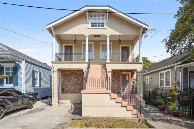 view of front of house featuring covered porch, brick siding, fence, and stairway