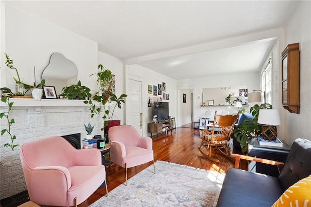 living room with a brick fireplace and wood finished floors