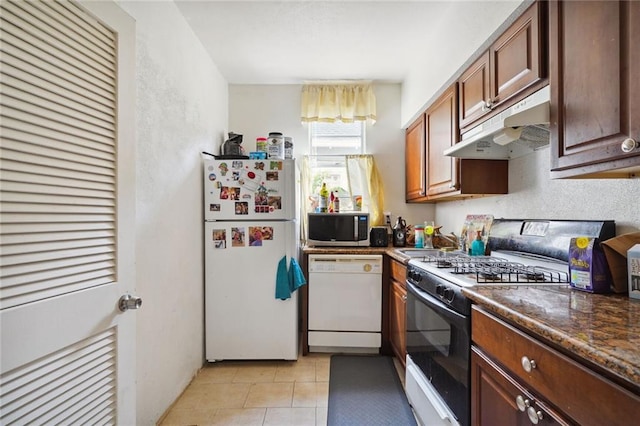 kitchen with dark countertops, white appliances, under cabinet range hood, and light tile patterned flooring