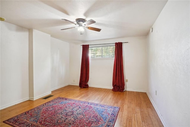 unfurnished room featuring baseboards, hardwood / wood-style floors, visible vents, and a ceiling fan