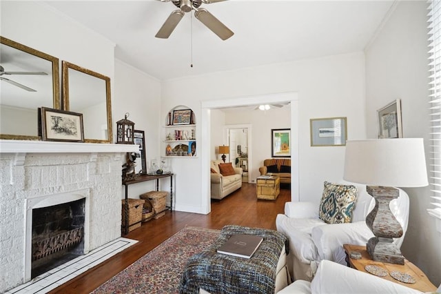 living area with ceiling fan, a fireplace, ornamental molding, and wood finished floors