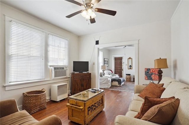 living area with ornamental molding, cooling unit, wood finished floors, and a ceiling fan