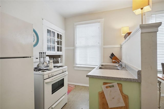 kitchen with white appliances, light countertops, a sink, and baseboards