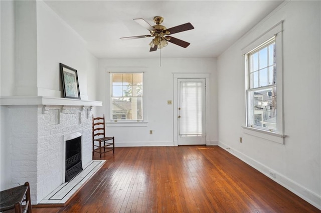 unfurnished living room with plenty of natural light, a fireplace, baseboards, and hardwood / wood-style flooring