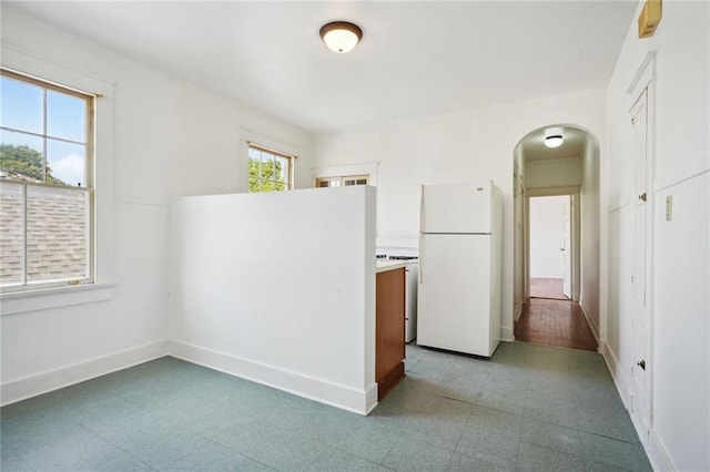 kitchen with tile patterned floors, baseboards, arched walkways, and freestanding refrigerator