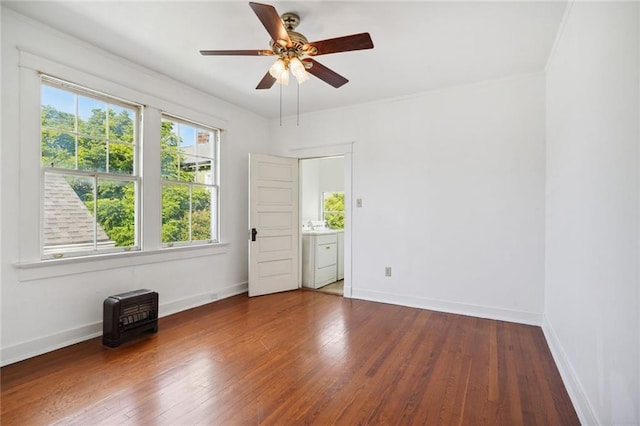 spare room featuring wood-type flooring, washing machine and clothes dryer, baseboards, and ceiling fan