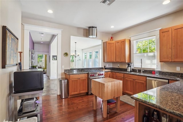 kitchen featuring appliances with stainless steel finishes, a healthy amount of sunlight, sink, a notable chandelier, and hanging light fixtures