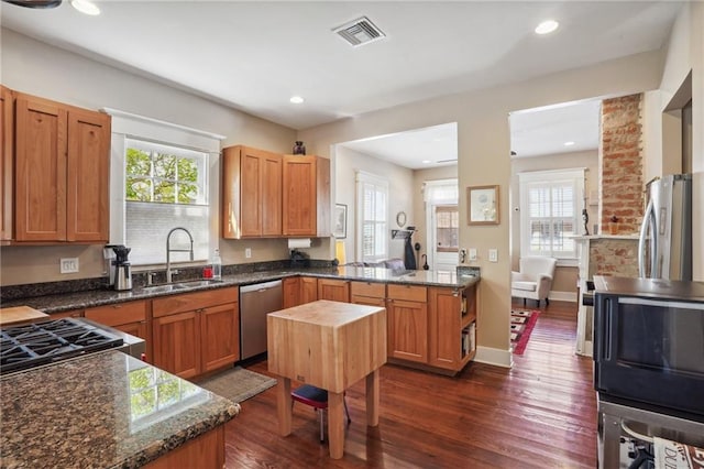 kitchen with dark stone countertops, a wealth of natural light, sink, and stainless steel appliances