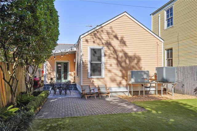 rear view of property featuring a lawn, a patio area, and french doors