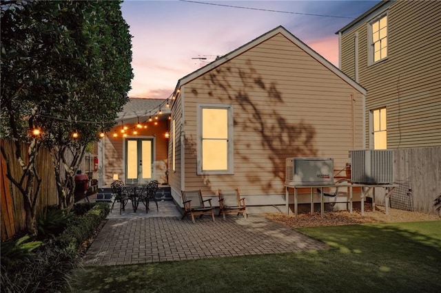 back house at dusk featuring a lawn and a patio