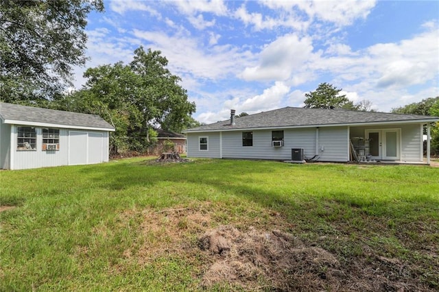 back of house with a yard, an outbuilding, and central AC unit