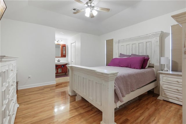 bedroom with ceiling fan, sink, light wood-type flooring, and ensuite bathroom