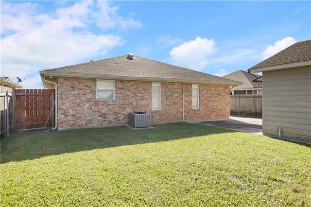 rear view of property with central air condition unit, a patio area, and a yard