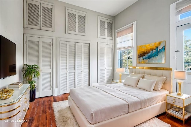 bedroom with dark hardwood / wood-style floors and multiple closets